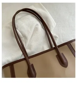 Detail of reinforced stitching on brown synthetic leather tote bag handles