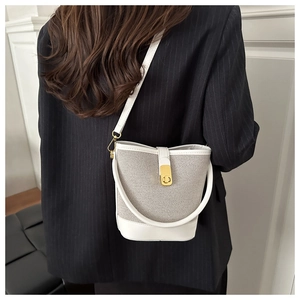 Detail view of contrast stitching bucket bag featuring gold hardware and a leather strap