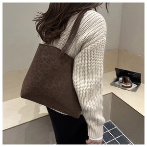 Detail of a brown leopard print tote bag made of suede leather on a model shoulder