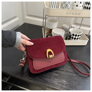 Close-up of wine red crossbody bag with golden U-shaped buckle and suede leather textures