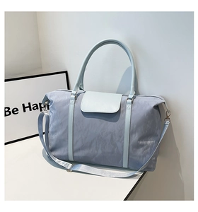 Detail of light blue travel bag with wrinkled nylon texture and adjustable shoulder strap