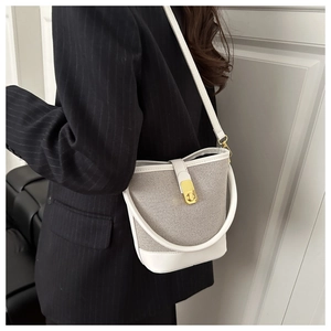 Detail showing the gray textured fabric and gold twist lock on this chic bucket bag