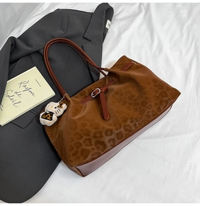 Detail view of leopard print tote bag with plush charm and smooth leather trim