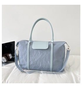 Close-up of light blue travel bag with wrinkled texture and golden hardware