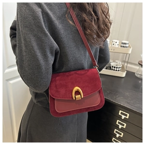 Detail of burgundy vintage crossbody bag showing suede texture and golden metal buckle