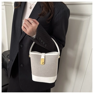 Detailed view of white leather and woven fabric bucket bag with gold clasp and top handle