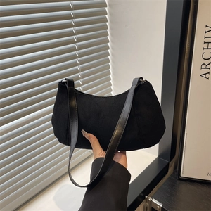 Minimalist black matte suede hobo bag shown in a stylish lifestyle setting with soft lighting