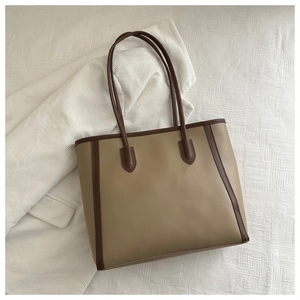 Detail of khaki tote bag with dark brown trim on white corduroy textured background