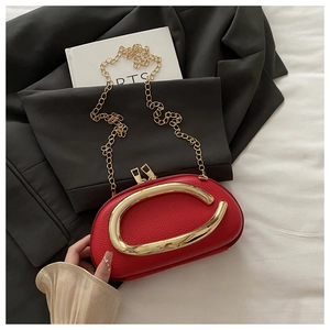 Detail of red lychee pattern crossbody bag with C-shaped gold handle and chain strap