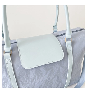 Detailed close-up of light blue textured fabric and faux leather straps on a travel bag