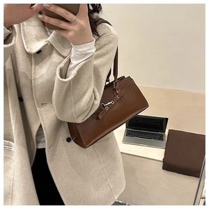 Detail of brown vintage shoulder bag with glossy finish and horizontal metal buckle design