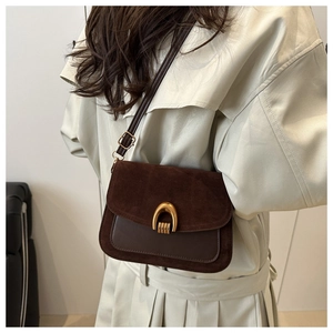 Detail of dark brown suede and leather crossbody bag with a gold horseshoe buckle