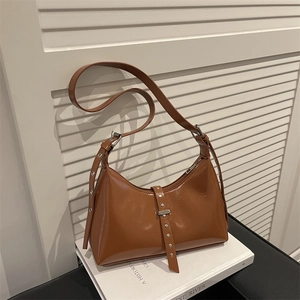Sac hobo en cuir synthétique marron brillant avec clous argentés et boucle sur un livre
