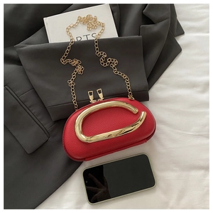 Detail of red litchi leather bag featuring a large gold metal handle and chain strap