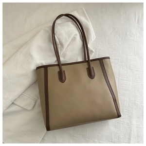Detail of camel tote bag with dark brown handles on white corduroy background