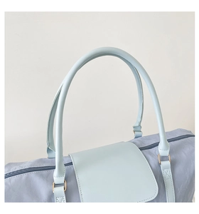 Detail view of a light blue nylon travel bag with dual handles and gold metal hardware