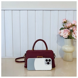 Detail showing Burgundy small shoulder bag with leather texture and gold buckle next to a phone