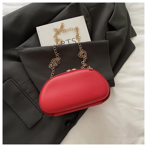 Top view of red lychee grain leather evening bag with golden chain on grey suit