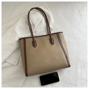 Detailed top view of large beige tote bag with brown leather trim on plaid fabric