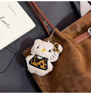 Plush Hello Kitty pendant with leopard print bow on a brown tote bag handle
