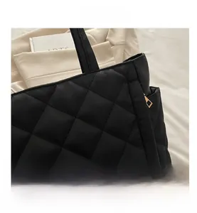 Detail shot of black quilted tote bag featuring a metallic zipper and elegant fabric texture