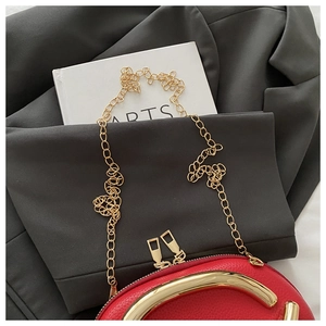 Detailed macro view of the bright red pebble leather and golden hardware of the chain bag