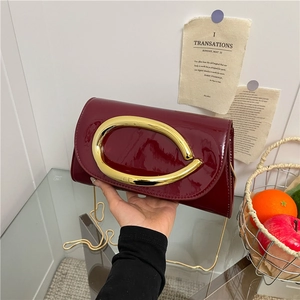 Burgundy patent leather crossbody bag with oversized gold handle and chain strap