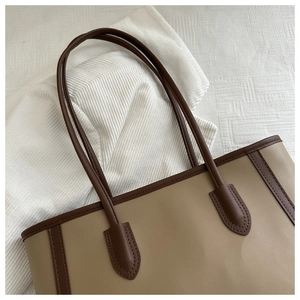 Close-up of contrast stitch on faux leather tote bag with long handles and brown trim