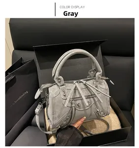 Detail of grey vintage motorcycle bag with stud accents and leather tassels in luxury setting