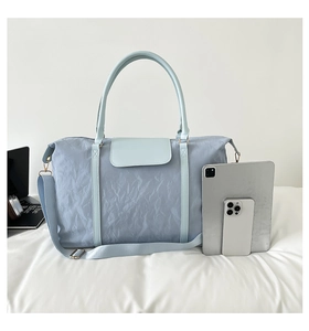 Light blue large travel bag next to a tablet showing spacious interior storage capacity