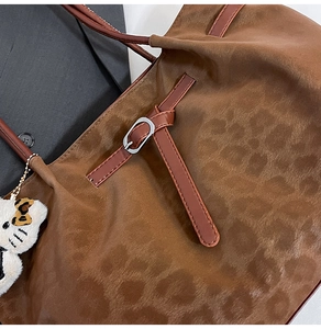 Close-up of leopard pattern suede tote bag with brown leather strap and silver buckle