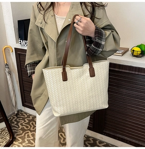 Close-up of cream woven tote bag with contrast brown leather strap and fine stitching