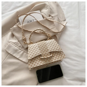 Detail of cream-colored textured mini square bag with brown circle patterns and hardware