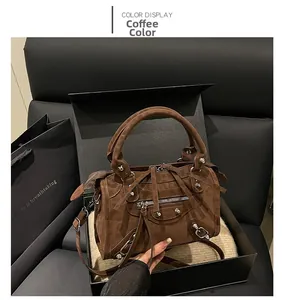 Detailed view of coffee brown suede motorcycle bag with silver studs and tassel in a gift box