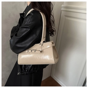 Détail d'un sac baguette en cuir crème avec boucle porté à l'épaule par un mannequin