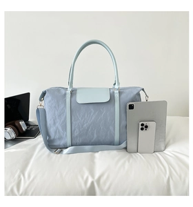 Close-up of light blue travel bag showing textured fabric with laptop and phone