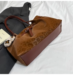 Detail of leopard print tote bag with brown leather trim and cute cat plush charm