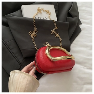 Detail of red pebbled leather capsule bag with gold metal handle on a black blazer