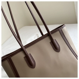 Detail of reinforced stitching and brown trim on the beige large capacity tote bag