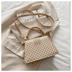 Close-up of elegant trapezoid crossbody bag with vintage monogram and gold hardware