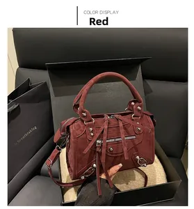 Detail of burgundy leather handbag featuring silver studs and fringe in premium box setting