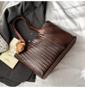 Detail view of coffee brown tote bag with premium leather woven texture and bear charm