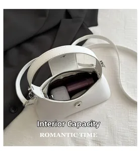 Interior view of the white crescent bag showing daily capacity for earbuds and lipstick