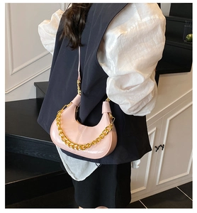 Macro shot of pink glossy patent leather hobo bag with bold gold decorative chain strap