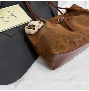 Detail of leopard print tote bag with plush kitten charm and premium hardware accents