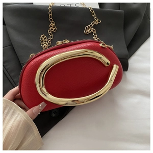 Detail of red pebbled leather bag featuring a large golden C-shaped handle and chain strap