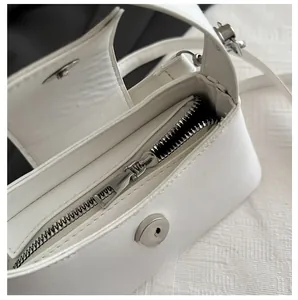 Detail view of smooth silver-tone zipper and white lychee texture on baguette bag