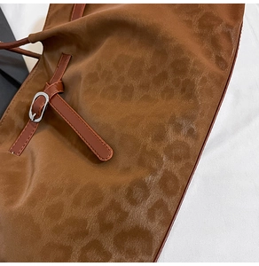 Detailed close-up of dark brown leopard embossed tote with silver metal buckle detail