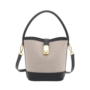 Chic beige canvas bucket bag with black leather trim and elegant gold twist lock