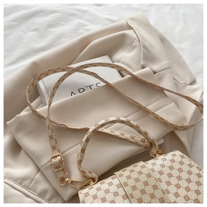 Detail view of cream crossbody bag with brown floral pattern and gold metal hardware